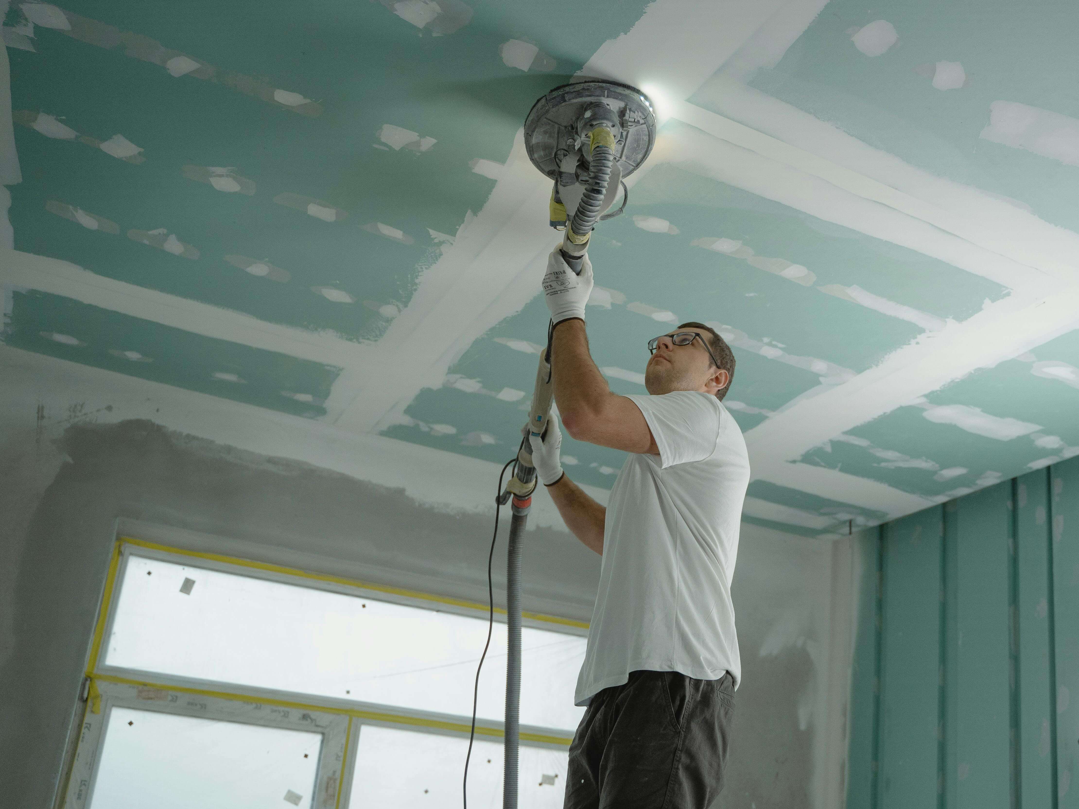 Another worker is completing work on a ceiling